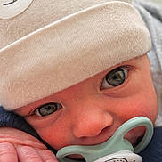 Ayden participe au concours pour gagner de l'argent avec cette photo : baby, close_up, pacifier, hat, beige, blanket, cute, infant, face, eyes, hand, soft_texture, warm, child, newborn, cozy, portrait, indoors, sucking, clothing