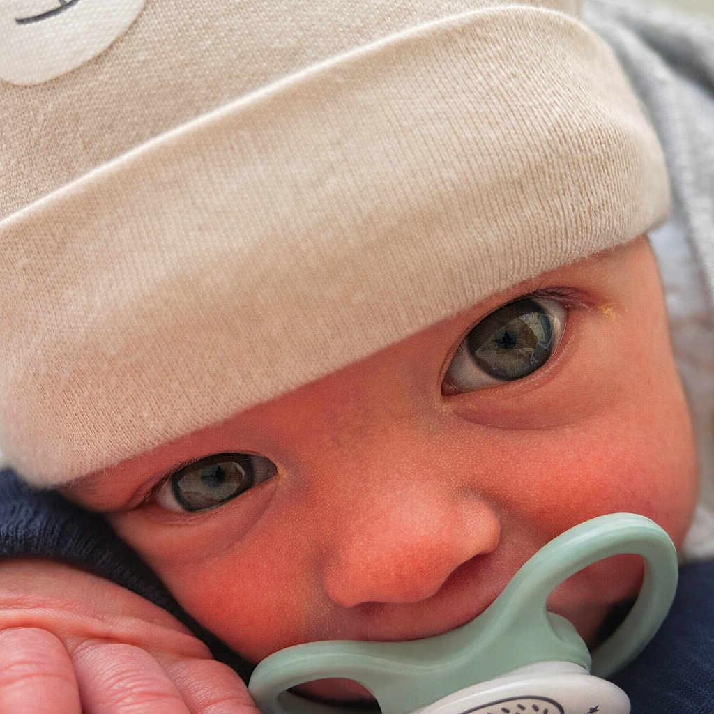 Ayden participe au concours pour gagner de l'argent avec cette photo : baby, close_up, pacifier, hat, beige, blanket, cute, infant, face, eyes, hand, soft_texture, warm, child, newborn, cozy, portrait, indoors, sucking, clothing