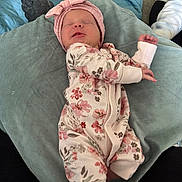 Athena Raven joined the competition — help win amazing prizes! baby, newborn, infant, sleeping, onesie, floral_pattern, headband, pink, cushion, blanket, soft_fabric, indoor, child, person, resting, cozy, cute, small_hands, peaceful, portrait