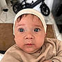 baby, child, face, hat, sweater, indoor, blue_eyes, curious, closeup, portrait, infant, hands, expression, skin, headwear, person, floor, bicycle, background, tile_floor