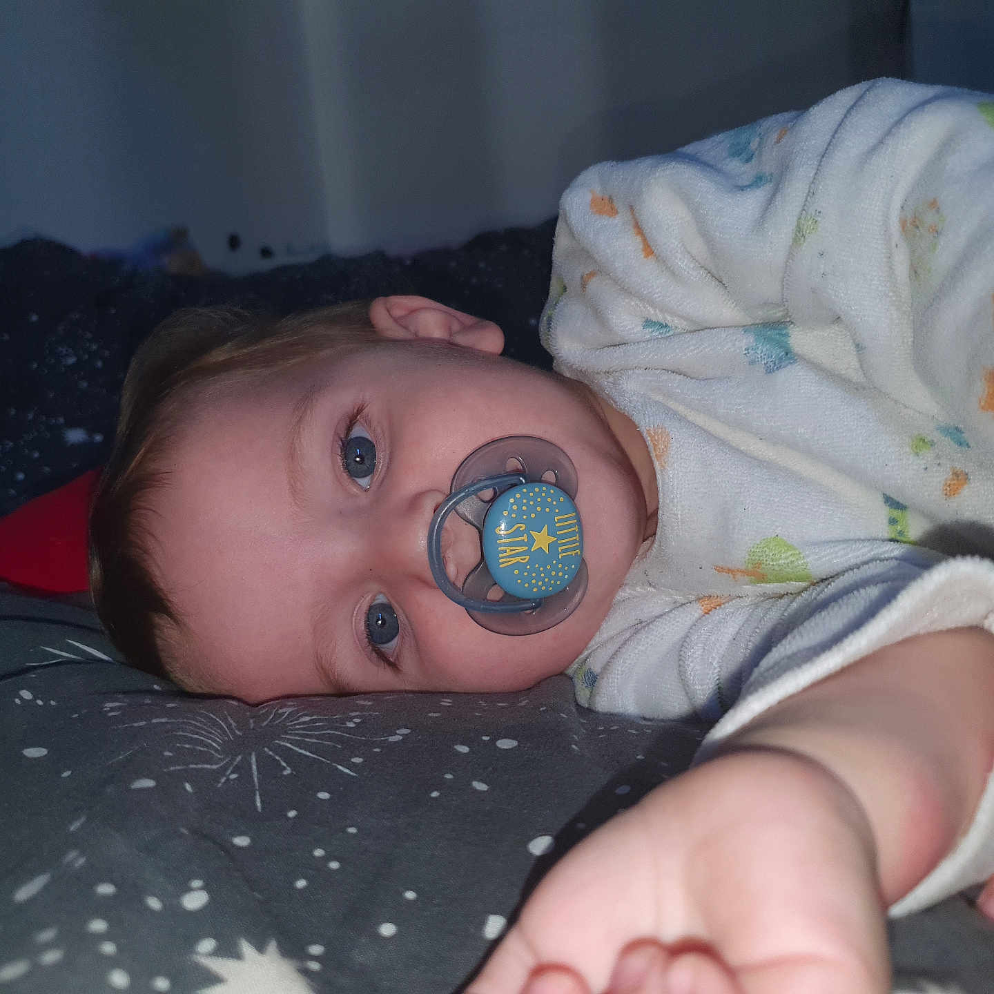 Adrian participe au concours pour gagner de l'argent avec cette photo : baby, bedtime, blanket, blue_eyes, child, comfort, cozy, cute, face, hand, indoors, infant, lying_down, pacifier, pajamas, resting, sleep, sleepwear, soft_lighting, star_pattern