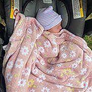 Luna is registered to the contest to win money with this photo: newborn, baby, blanket, pink, floral, hat, car_seat, sleeping, child, infant, cozy, striped, warning_label, fabric, outdoor, resting, head, wrapped, soft, person