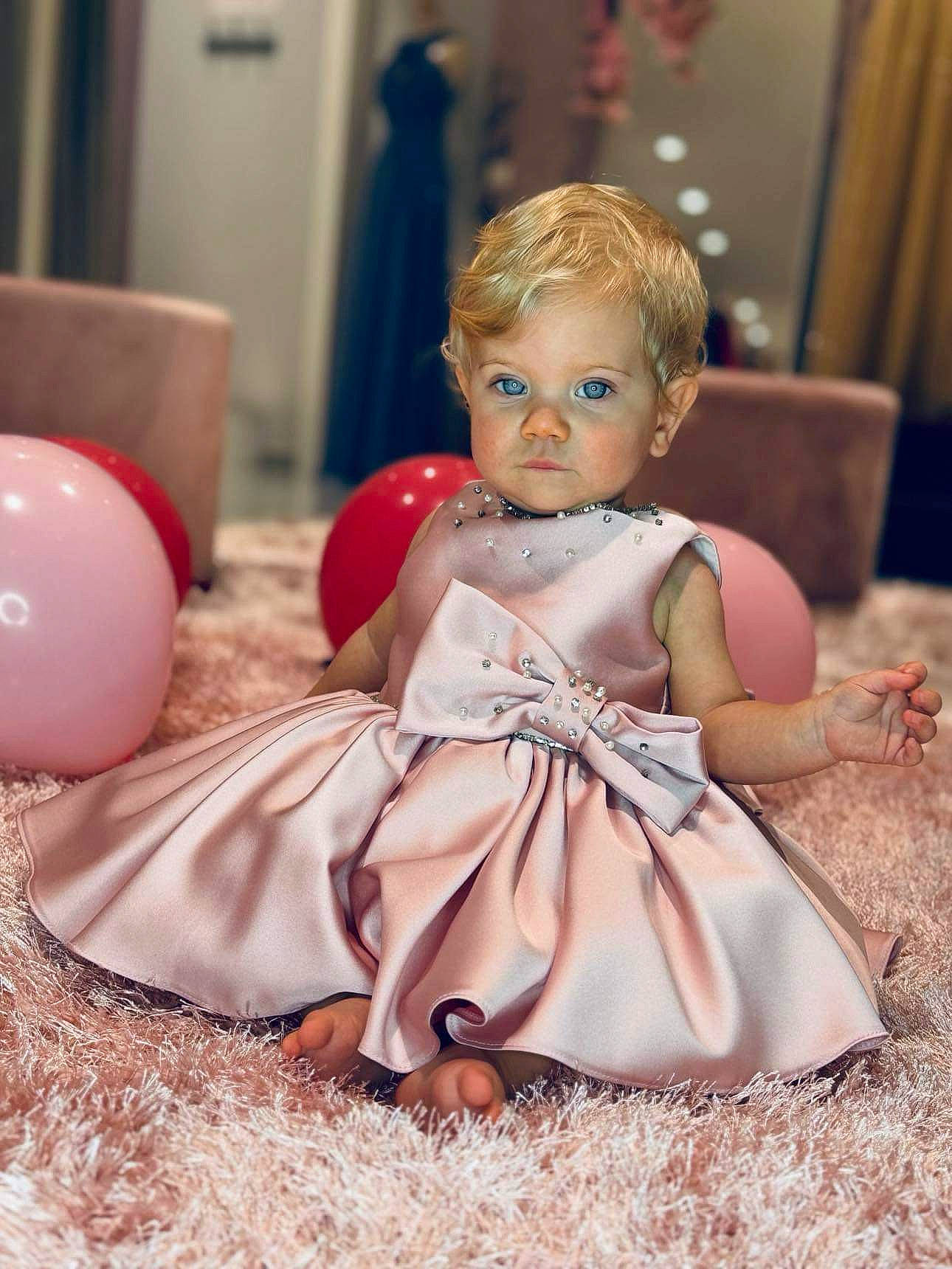 Alayna participe au concours pour gagner de l'argent avec cette photo : baby, blond, child, curtain, doll, dress, event, eye, facial_expression, fun, happy, headpiece, iris, peach, person, pink, sitting, skin, toddler, toy