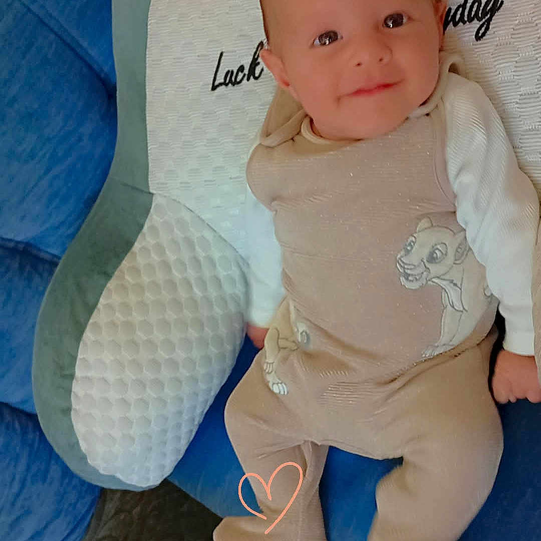 De Jesus Alves Leo participe au concours pour gagner de l'argent avec cette photo : baby, blue, child, comfort, couch, cute, face, footwear, green, heart, home, infant, lying, pajamas, person, pillow, smiling, soft, text, white