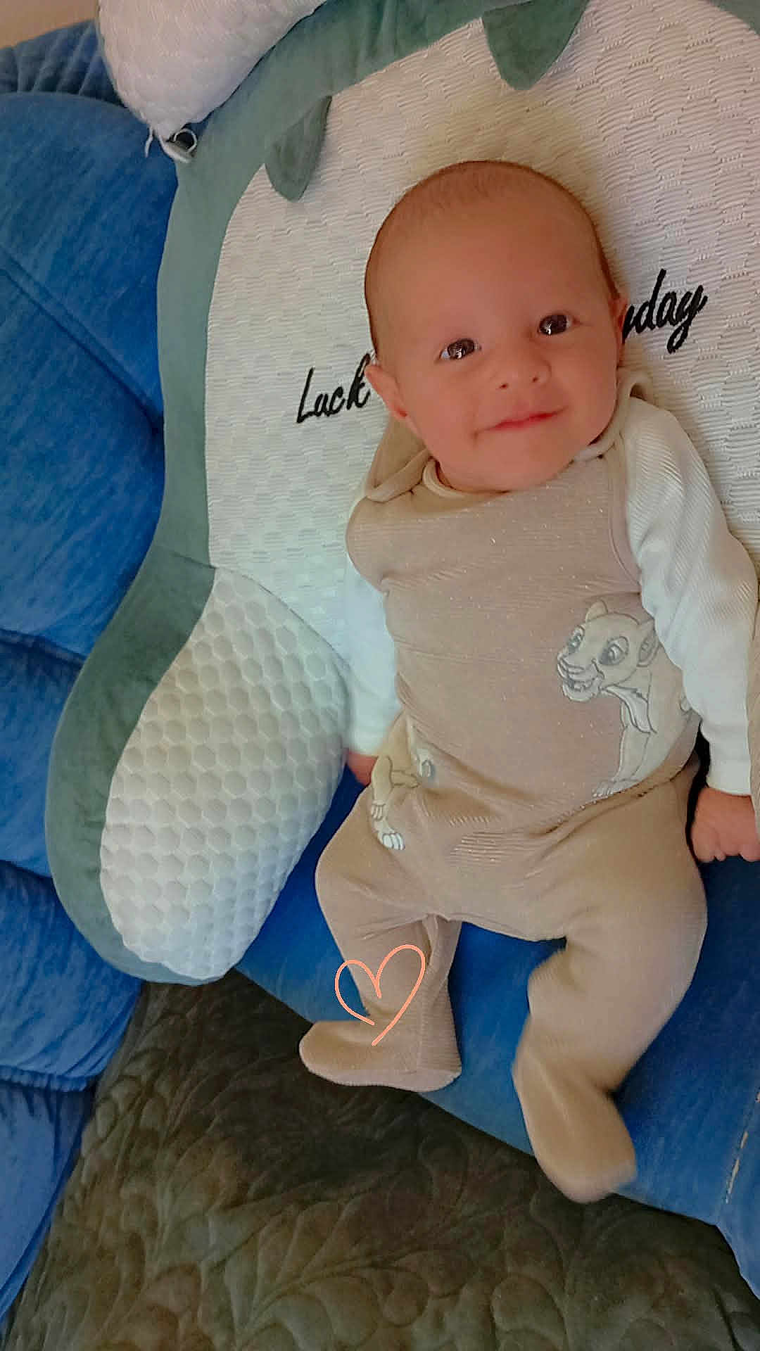 De Jesus Alves Leo participe au concours pour gagner de l'argent avec cette photo : baby, infant, smiling, pajamas, couch, pillow, blue, green, white, face, person, child, home, cute, footwear, text, soft, comfort, heart, lying