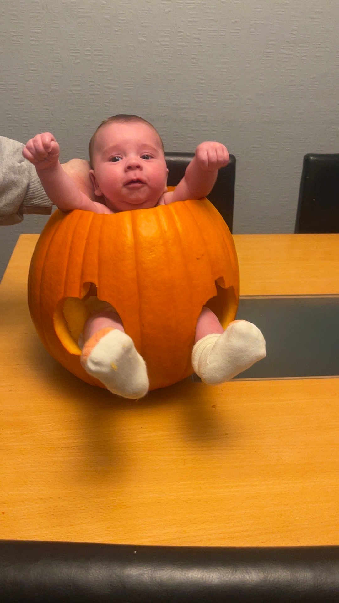 Theodore is registered to the contest to win money with this photo: baby, pumpkin, table, sock, hand, orange, face, child, holiday, autumn, cute, indoor, celebration, person, furniture, chair, smile, skin, holiday_decoration, festive