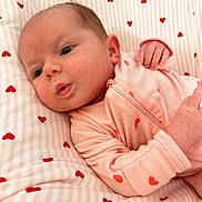 Isla is registered to the contest to win money with this photo: baby, infant, newborn, onesie, pink, hearts_pattern, bedding, blanket, crib, cute, adorable, face, eyes, hand, portrait, closeup, lying_down, soft, sleepwear, nursery