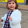 child, girl, red_bow, white_jacket, plaid_dress, smiling, outdoor, sidewalk, flower, young_child, happy, portrait, casual_clothing, urban, cute, person, fashion, daylight, headwear, motion_blur