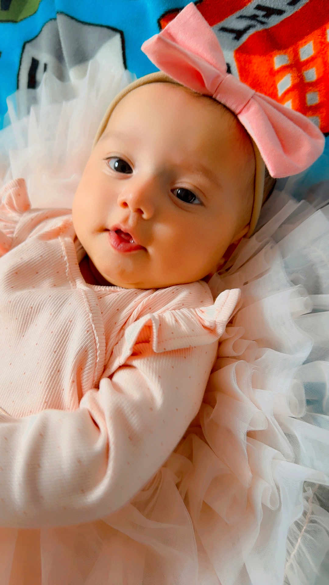 Zaynah joined the competition — help win amazing prizes! adorable, baby, blanket, bow, child, close_up, colorful_background, cute, face, happy, headband, indoors, infant, lying_down, newborn, peaceful, pink_clothing, portrait, ruffles, soft_fabric
