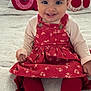 baby, child, smiling, red_dress, white_shoes, leggings, bed, pillow, decorative_pillow, donut_pillow, cherry_pillow, indoor, cute, happy, portrait, infant, sitting, clothing, face, person