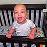Braylen is registered to the contest to win money with this photo: baby, child, crib, nursery, smiling, happy, standing, infant, portrait, face, hands, white_shirt, wooden_crib, mattress, animal_pattern, indoor, home, baby_bed, joyful, photography