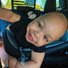 baby, infant, child, smiling, car, car_seat, safety_harness, pacifier, toy, portrait, close_up, indoor, vehicle, seated, happy, blue_eyes, black_clothing, arms, head, family_photo