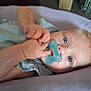baby, blue_eyes, child, close_up, clothing, curious, cute, face, hands, indoor, infant, light_blue, lying_down, pacifier, person, portrait, relaxed, skin, soft_surface, young
