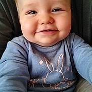 Célestin a rejoint le concours — aidez-le/la à gagner de superbes lots ! baby, blue_clothing, bunny_design, candid, casual, cheeks, child, closeup, cute, face, happy, indoors, infant, light_skin, long_sleeve, person, portrait, sitting, smiling, young_child