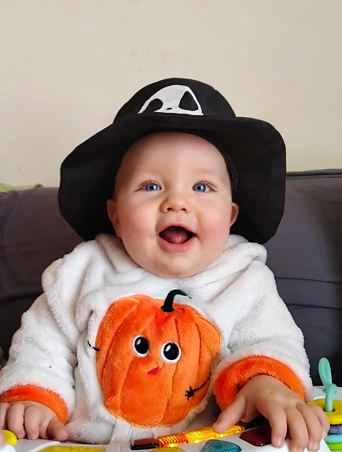 Célestin participe au concours pour gagner de l'argent avec cette photo : baby, child, smiling, hat, black_hat, ghost_face, hoodie, pumpkin, orange, toy, keyboard, blue_eyes, happy, cute, indoor, person, infant, clothing, hands, playing