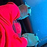 animal_slippers, blue_background, bundled_up, car, car_seat, casual, child, cozy, fuzzy_slippers, hooded_outfit, indoor, leather_seat, portrait, red_clothing, seated, small_person, toddler, travel, vehicle_interior, winter_clothing