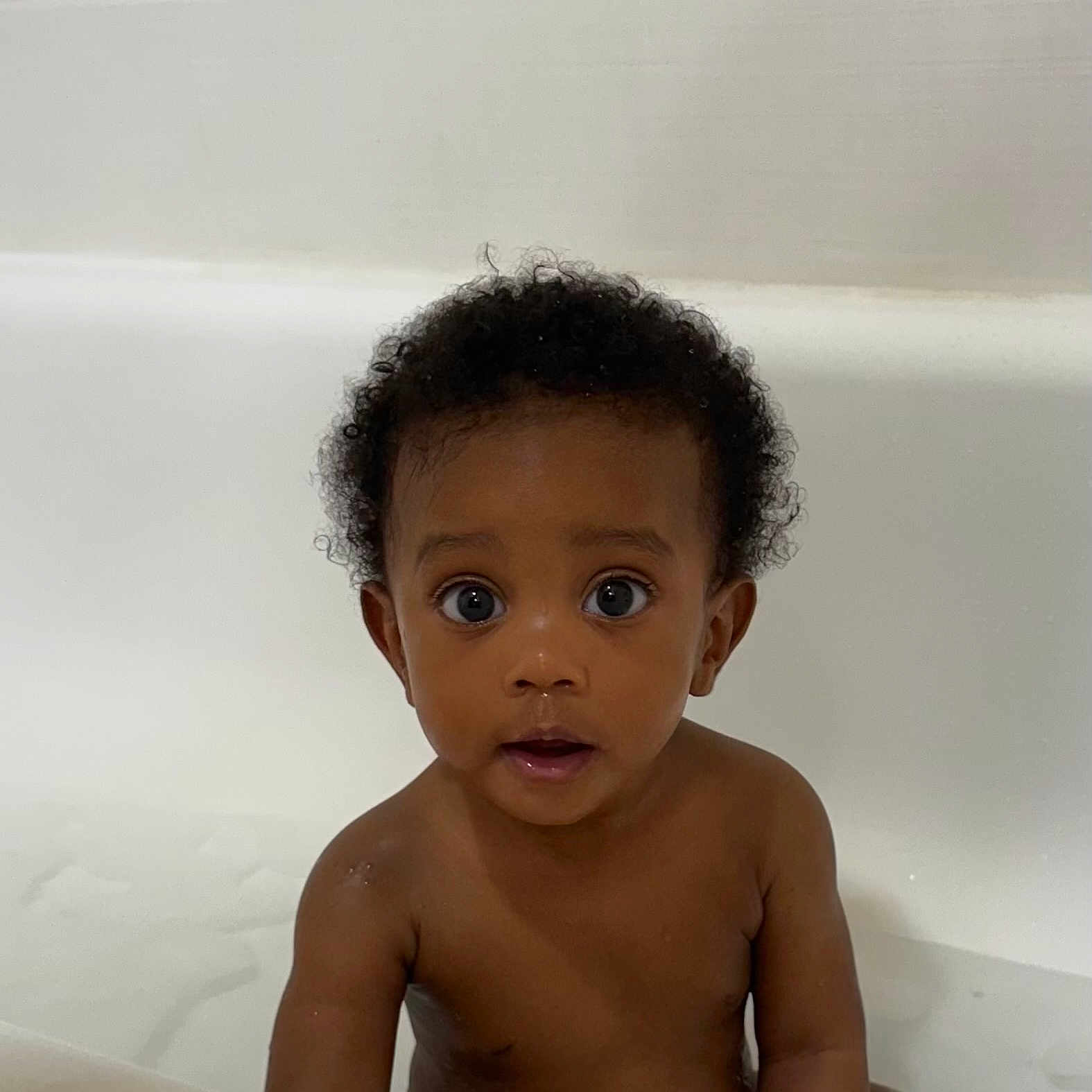 Kahyir is registered to the contest to win money with this photo: baby, bath_time, bathtub, child, curious, curly_hair, cute, expression, eyes, face, indoor, innocent, looking_at_camera, naked_torso, person, portrait, sitting, skin, water, young_child