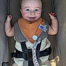 baby, infant, child, smiling, happy, portrait, car_seat, harness, bib, pacifier, toy, clothing, blue_eyes, brown_hair, sitting, indoors, vehicle, safety_belt, close_up, photography