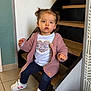 child, toddler, pigtails, pink_cardigan, heart_tshirt, sneakers, sitting, staircase, wooden_stairs, tiled_floor, indoor, curious_expression, portrait, young_child, buttons, blue_leggings, white_shoes, wall, doorframe, cozy