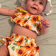 Emily Rose is registered to the contest to win money with this photo: baby, child, smiling, sunhat, sunflower, clothing, infant, cute, portrait, happy, lying_down, skin, apparel, toddler, face, hand, fabric, summer, headwear, closeup