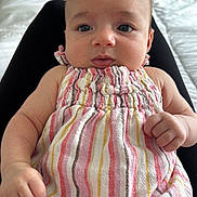 Bellamy is registered to the contest to win money with this photo: baby, infant, child, dress, striped_clothing, person, face, eyes, hand, fist, lap, bed, blanket, indoor, furniture, soft, curious, closeup, skin, cute