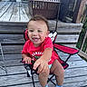 toddler, child, smiling, red_shirt, chair, folding_chair, wooden_deck, outdoor, umbrella, happy, baby, socks, person, seat, wood, hand, face, grass, balcony, railing