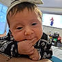 baby, infant, child, close_up, hand, fingers, headband, bow, clothing, living_room, television, window, furniture, person, bed, blanket, home, indoor, face, cute