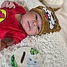 baby, infant, red_clothing, brown_hat, cartoon_face, fluffy_blanket, cute, sleepy, milestone, one_month, elephant_illustration, soft_texture, portrait, child, lying_down, indoors, close_up, headwear, adorable, newborn