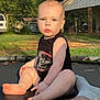 baby, child, infant, trampoline, outdoor, sunlight, blue_eyes, black_onesie, skin, hair, grass, netting, blanket, foot, hand, face, person, nature, yard, house