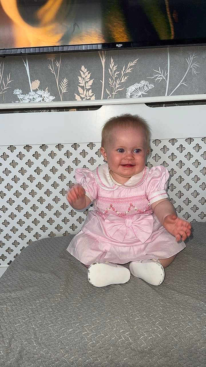 Vienna joined the competition — help win amazing prizes! baby, child, pink_dress, smiling, sitting, clapping, white_shoes, indoor, wallpaper, floral_pattern, lattice, joyful, cute, portrait, infant, person, home, decor, happy, small_child