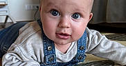 Louka a rejoint le concours — aidez-le/la à gagner de superbes lots ! baby, blanket, blue_eyes, chubby_cheeks, close_up, couch, curious_expression, cute, denim, floor, gaze, hand, indoor, infant, living_room, overalls, play_mat, portrait, smiling, tummy_time