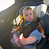 baby, bare_feet, blue_eyes, buckle, car_interior, car_seat, child, clothing, cute, denim_overalls, family, headrest, infant, portrait, safety, seatbelt, sunlight, surprised_face, toddler, window
