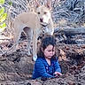 alert, animal, blue_shirt, branches, brown_earth, casual, child, curious, daylight, dirt, dog, exploration, forest, leaves, nature, outdoor, pet, playing, trees, young_girl