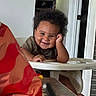 baby, high_chair, smile, curly_hair, indoor, person, child, table, door, window_blinds, furniture, hand, face, clothing, seat, happy, domestic, playful, young, infant