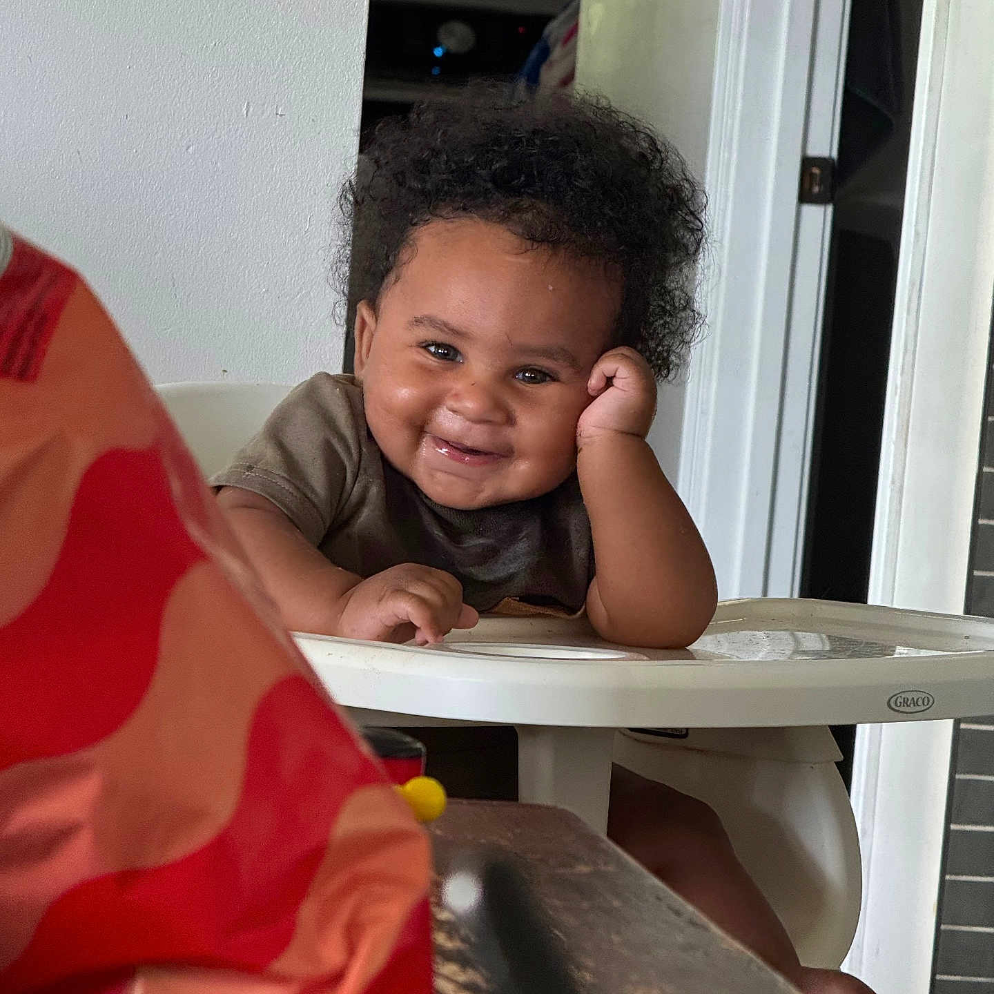 Michaleon joined the competition — help win amazing prizes! baby, high_chair, smile, curly_hair, indoor, person, child, table, door, window_blinds, furniture, hand, face, clothing, seat, happy, domestic, playful, young, infant