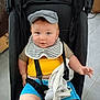 baby, child, stroller, cap, bib, blue_eyes, yellow_shirt, blue_shorts, plush_toy, elephant_toy, indoor, floor_tiles, baby_seat, cute, person, infant, clothing, seat_belt, hand, face