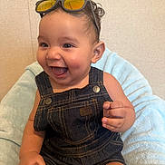 Dante Valentin joined the competition — help win amazing prizes! baby, bright_eyes, child, clothing, curly_hair, cute, denim_overalls, face, happy, indoor, infant, joyful, light_blue_blanket, person, portrait, sitting, small_hand, smile, sunglasses, young