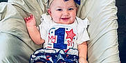 Willow is registered to the contest to win money with this photo: baby, child, smiling, headband, bow, cushion, clothing, patterned_clothing, stars, stripes, floor, wooden_floor, sitting, cute, infant, posing, indoors, comfort, happy, portrait