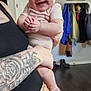 Willow joined the competition — help win amazing prizes! baby, child, laughing, smiling, headband, white_bow, tattoo, adult, holding, indoor, home, jacket, boots, floor, door, wall_art, person, infant, cute, happy