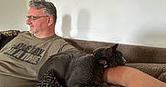 Baby joined the competition — help win amazing prizes! arm, beard, casual_clothing, cat, comfort, couch, cushion, glasses, gray_cat, home, indoor, living_room, man, pattern, portrait, relaxed, resting, seated, short_hair, wall_art