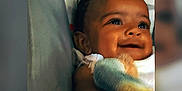 Gracie is registered to the contest to win money with this photo: baby, blanket, cartoon, child, closeup, colorful, comfort, cute, expression, eyes, face, happy, indoors, infant, portrait, skin, smiling, soft, warmth, young