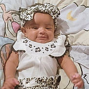 Gracie is registered to the contest to win money with this photo: baby, blanket, cartoon_character, child, comfortable, cute, happy, headband, indoors, infant, leopard_print, lying_down, patterned_clothing, playful, portrait, small_child, smiling, soft_toys, toddler, white_clothing