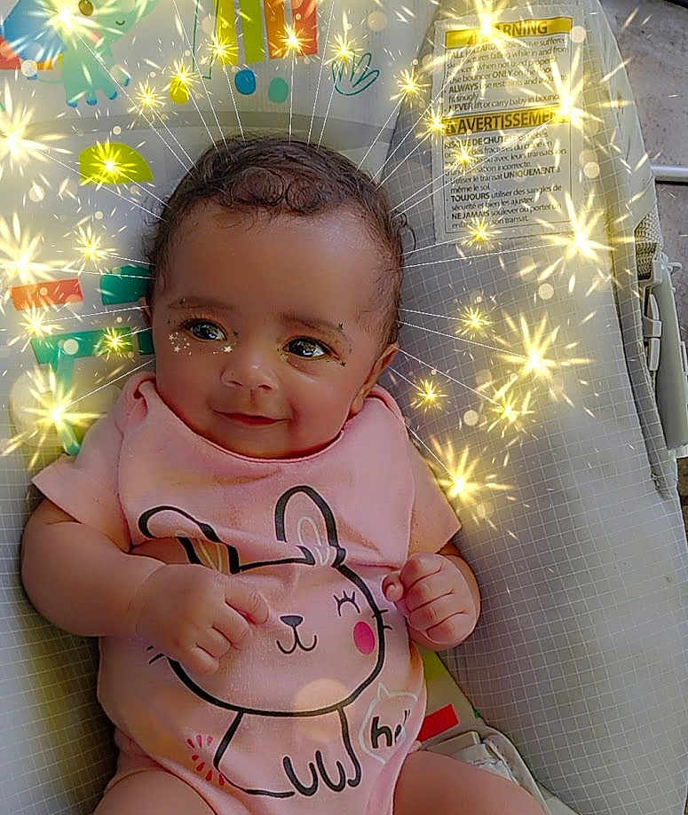 Gracie joined the competition — help win amazing prizes! baby, child, infant, onesie, pink_clothing, bunny_design, sparkles, magic_effect, smile, sitting, baby_seat, colorful_background, cute, portrait, happy, indoors, face, hand, skin, hair