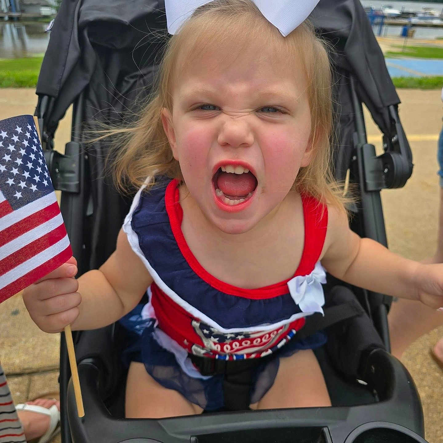 Harper is registered to the contest to win money with this photo: architecture, baby, city, clothing, face, flag, footwear, grass, head, nature, outdoors, park, person, photography, plant, portrait, shoe, stroller, summer, t_shirt