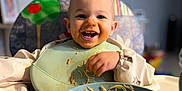 Maëlio a rejoint le concours — aidez-le/la à gagner de superbes lots ! toddler, child, high_chair, spaghetti, food, messy, smiling, happy, face, bib, plate, noodles, indoor, table, eating, person, clothing, utensils, kitchen, home