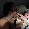 Alaric joined the competition — help win amazing prizes! baby, infant, adult, parent, family, cuddling, smiling, happy, playful, bed, bedroom, blanket, pillow, dinosaur_pattern, glasses, barefoot, indoor, portrait, close_up, caregiving