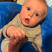 Grayson joined the competition — help win amazing prizes! baby, child, infant, blue_cushion, plush, indoor, curious, reaching, face, hand, foot, rosy_cheeks, seated, clothing, person, portrait, closeup, head, expression, eyewear