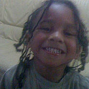 Enzo participe au concours pour gagner de l'argent avec cette photo : child, smile, braided_hair, couch, indoor, happy, person, face, casual_clothing, living_room, furniture, childhood, portrait, young, joy, hair, seated, home, relaxed, cute