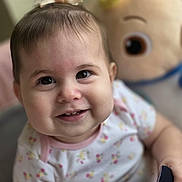 Luna is registered to the contest to win money with this photo: baby, child, smiling, face, hair_bow, plush_toy, indoor, cute, portrait, infant, happy, clothing, patterned_shirt, closeup, person, young_child, soft_lighting, background_blur, toy, cheerful