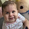 baby, child, smiling, face, hair_bow, plush_toy, indoor, cute, portrait, infant, happy, clothing, patterned_shirt, closeup, person, young_child, soft_lighting, background_blur, toy, cheerful